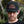 Load image into Gallery viewer, "Person wearing a black trucker hat with a leather patch featuring the logo 'Kentzo Koffee,' a mountain design, and the phrase 'Fuel Your Adventure.' The individual looks serious, standing against a blurred natural background of greenery and tree trunks, adding an adventurous and rugged vibe."