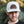 Load image into Gallery viewer, Person wearing a White trucker hat with a leather patch featuring the logo 'Kentzo Koffee,' a mountain design, and the phrase 'Fuel Your Adventure.' The individual looks serious, standing against a blurred natural background of greenery and tree trunks, adding an adventurous and rugged vibe.